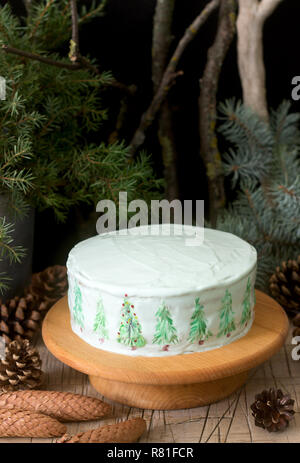 Festliche Kuchen mit gemalten Weihnachtsbaum auf einem dunklen Hintergrund der Zweige und Zapfen dekoriert. Im rustikalen Stil. Stockfoto