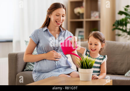 Schwangere Mutter und Tochter Bewässerung home Anlage Stockfoto