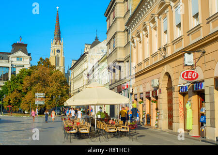 NOVI SAD, Serbien - 26. AUGUST 2017: Menschen bei Street Restaurant in Novi Sad. Der Name unserer Kirche im Hintergrund. Novi Sad ist die zweite Lar Stockfoto