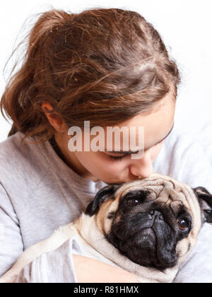 Ziemlich glücklich lächelnden Teenager Mädchen umarmt niedliche Mops Hund mit Liebe Stockfoto