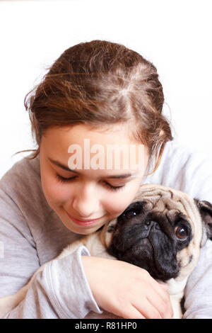 Ziemlich glücklich lächelnden Teenager Mädchen umarmt niedliche Mops Hund mit Liebe Stockfoto