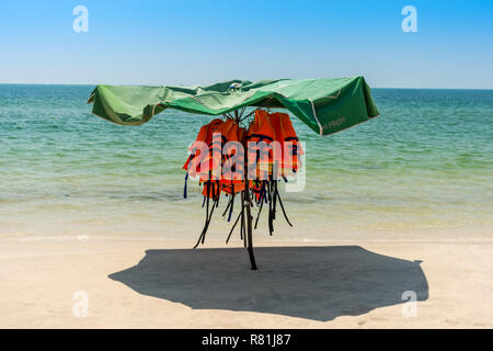 Persönliche floatation Geräte im Schatten von der Sonne unter einem Sonnenschirm auf einer leeren Strand. Stockfoto