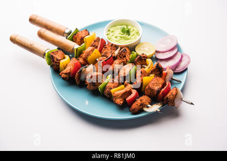 Chicken Tikka/skew Kebab. Traditionelle indische Gericht gekocht auf Holzkohle und Flamme, gewürzt & bunt garniert. Mit grüner Chutney und Salat serviert. Stockfoto