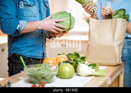 Junges Paar auspacken shopping Zurück mit frischem Grün Produkte auf die Küche zu Hause, 7/8-Bild ohne Gesicht Stockfoto
