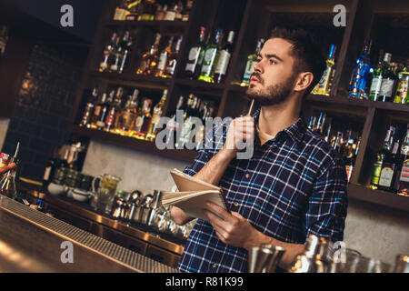 Junge Barkeeper stehen an der Theke holding Notebook denken Stockfoto