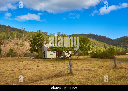 Ein altes Gehöft aus Zinn im Outback in Clarence Land von Bergen und Bäumen umgeben sind, New South Wales, Australien Stockfoto