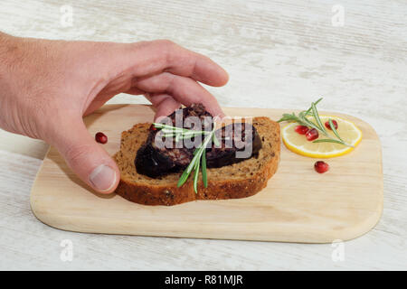 Männliche hand Sandwich mit Roggenbrot in Scheiben geschnitten und Blutwurst auf Holzplatte Stockfoto