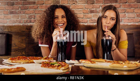 Porträt von zwei glückliche junge Frauen trinken alkoholfreie Getränke im Restaurant. Weibliche Freunde Mittagessen im Restaurant. Stockfoto