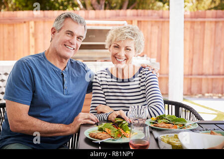 Senior weiß Paar sitzen beim Mittagessen im Garten mit Blick auf die Kamera Stockfoto