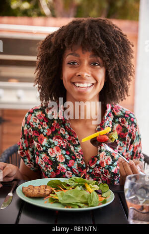 Junge schwarze Frau das Mittagessen an einem Tisch draußen, vertikal Stockfoto
