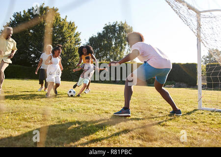 Multi-Generation schwarze Familie Fußball spielen in einem Garten Stockfoto