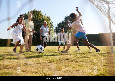 Multi-Generation schwarze Familie Fußball spielen in einem Garten Stockfoto