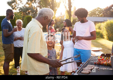 Opa und Enkel sprechen durch den Grill in einer Familie Grill Stockfoto