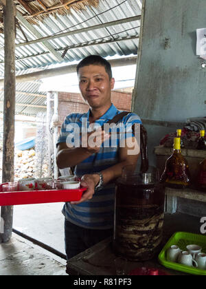 Junge vietnamesische Mann mit einer Stichprobe von Snake Drink an Touristen in Hai Van Workshop die Cobra, die gemolken wird das Getränk in der Nähe von Cai zu machen V sein. Stockfoto