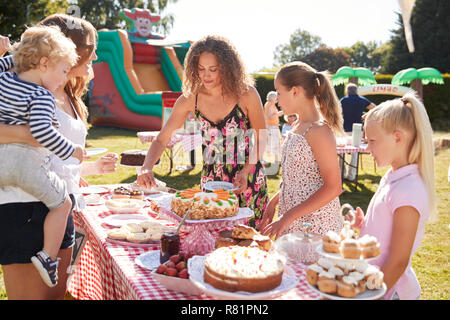 Kinder, die an Kuchen Abschaltdruck am beschäftigten Sommer Garten Fete Stockfoto