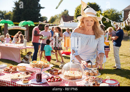 Reife Frau Dienen auf Kuchen Abschaltdruck am beschäftigten Sommer Garten Fete Stockfoto