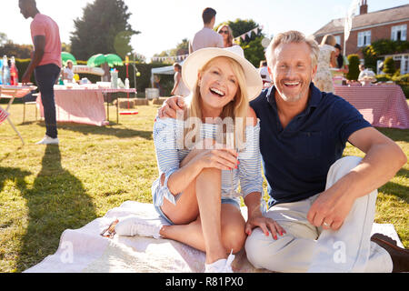 Portrait von Reifes Paar sitzt auf Teppich bei Sommer Garten Fete mit Getränken Stockfoto