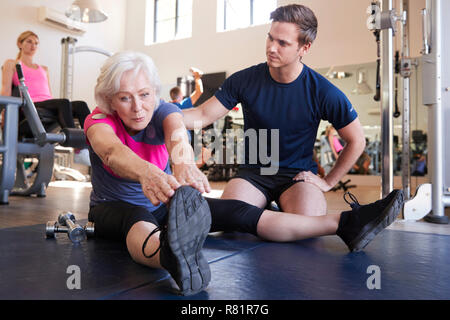 Ältere Frau trainieren im Fitnessraum mit Personal Trainer gefördert Stockfoto