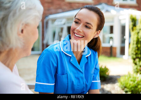 Ältere Frau sitzt auf der Bank und im Gespräch mit der Krankenschwester im Ruhestand Home Stockfoto