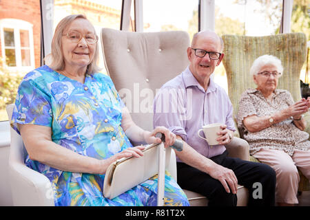 Portrait von männlichen und weiblichen Einwohner Sitzen auf Stühlen in der Lounge des Seniorenheims Stockfoto