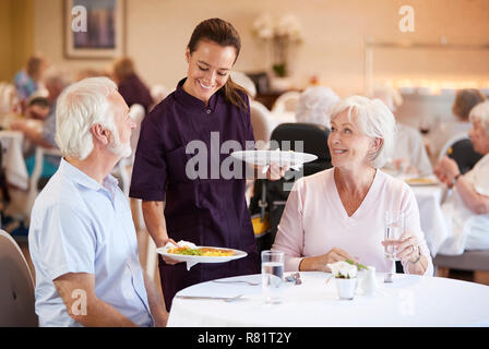 Senior Paar, serviert mit Essen durch die Pflegeperson im Speisesaal des Seniorenheims Stockfoto