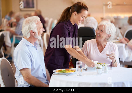 Senior Paar, serviert mit Essen durch die Pflegeperson im Speisesaal des Seniorenheims Stockfoto