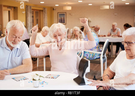 Ältere Frau gewinnen Spiel von Bingo im Ruhestand Home Stockfoto