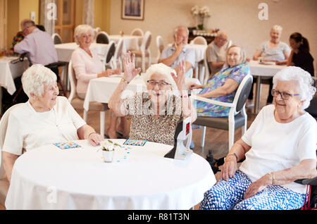 Ältere Frau gewinnen Spiel von Bingo im Ruhestand Home Stockfoto