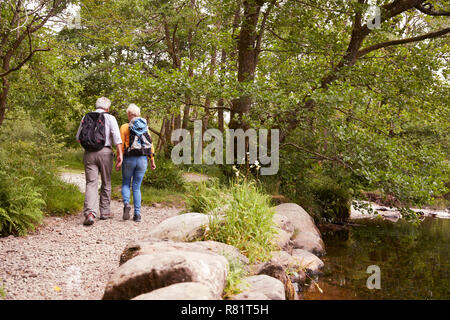 Ansicht der Rückseite des Senior Paar Wandern entlang Pfad am Fluss in England Lake District Stockfoto