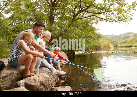 Familie auf Spaziergang mit Netzen in Fluss in England Lake District Stockfoto