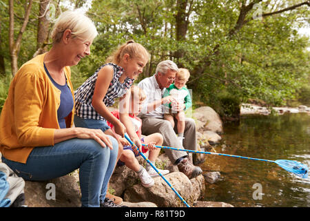 Großeltern mit Enkeln Fischen mit Treibnetzen in Fluss in England Lake District Stockfoto