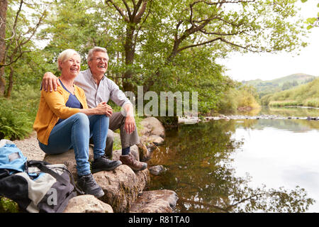 Senior Paar auf Wanderung Sitzen am Fluss in England Lake District Stockfoto