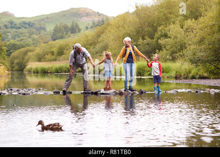 Großeltern mit Enkeln Fluß bei Wanderungen in England Lake District Stockfoto