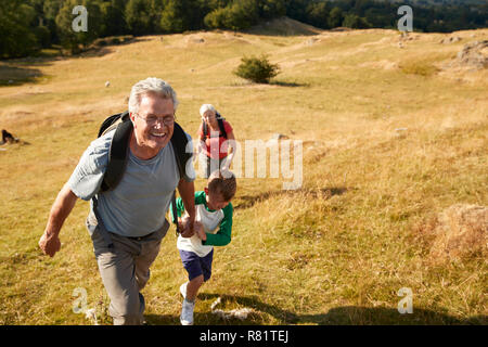 Großeltern mit Enkeln klettern Hügel auf Wanderung durch die Landschaft im Lake District in Großbritannien Zusammen Stockfoto