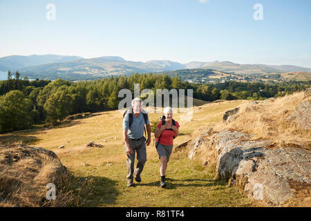 Senior Paar klettern Hügel auf Wanderung durch die Landschaft in Lake District in Großbritannien Stockfoto
