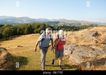 Senior Paar klettern Hügel auf Wanderung durch die Landschaft in Lake District in Großbritannien Stockfoto