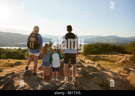 Rückansicht der Familie, die an der Oberseite des Hügels auf Wanderung durch die Landschaft im Lake District in Großbritannien Stockfoto