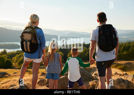 Rückansicht der Familie, die an der Oberseite des Hügels auf Wanderung durch die Landschaft im Lake District in Großbritannien Stockfoto