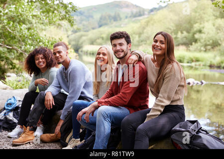 Multi-ethnische Gruppe von fünf jungen Erwachsenen Freunde eine Pause machen, sitzen auf den Felsen von einem Bach bei einer Wanderung, Porträt Stockfoto