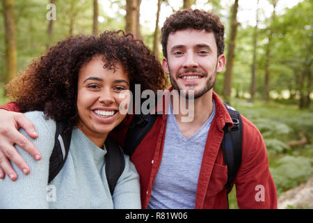 Ein junger Erwachsener Mixed Race Paar lächelt in die Kamera während einer Wanderung im Wald, Porträt Stockfoto