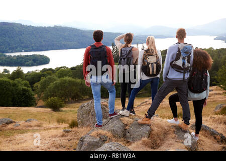 Eine Gruppe von fünf gemischten Rennen junge erwachsene Freunde bewundern Sie die Aussicht nach der Ankunft am Gipfel nach einer Bergwanderung, Blick nach hinten, in der Nähe von Stockfoto