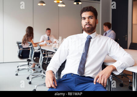 Portrait von Geschäftsmann in moderner Boardroom mit Kollegen treffen um den Tisch im Hintergrund Stockfoto