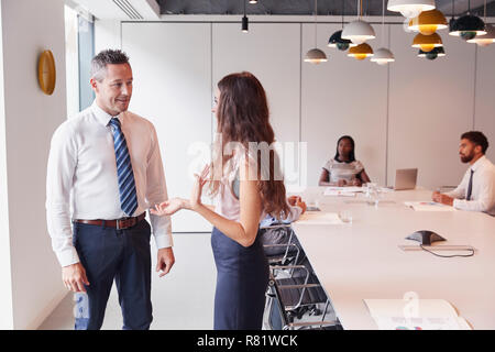 Kaufmann und Kauffrau In moderner Boardroom in informellen Diskussion mit Kollegen treffen um den Tisch im Hintergrund Stockfoto