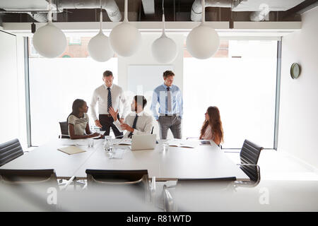 Unternehmer und Unternehmerinnen, um den Tisch in der modernen Sitzungssaal Stockfoto