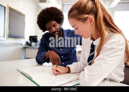 High School Tutor, Uniformierten Studentin Einzelunterricht am Schreibtisch im Klassenzimmer Stockfoto