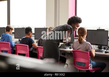 Lehrerin Überwachung Linie der High School Kursteilnehmer an Bildschirmen arbeiten In Computer Klasse Stockfoto