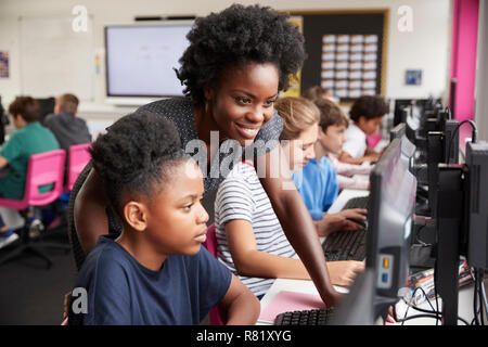 Lehrer helfen weiblichen Schüler der High School Kursteilnehmer an Bildschirmen arbeiten In Computer Klasse Stockfoto