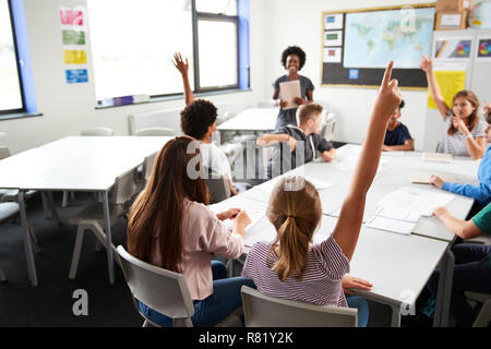 High School Schüler heben die Hände zu beantworten Frage durch den Lehrer im Klassenzimmer Stockfoto