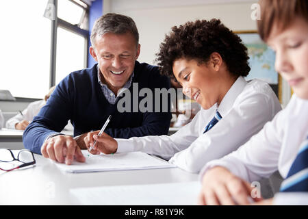 High School Tutor, männliche Student trägt Uniform Einzelunterricht am Schreibtisch Stockfoto