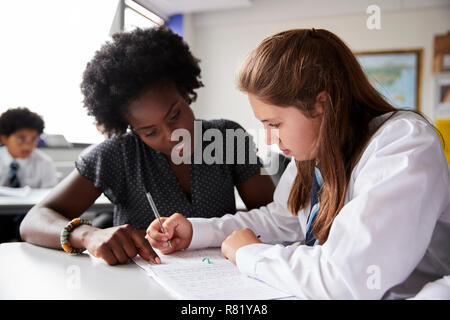 High School Lehrer geben Weibliche Student trägt Uniform Einzelunterricht am Schreibtisch Stockfoto